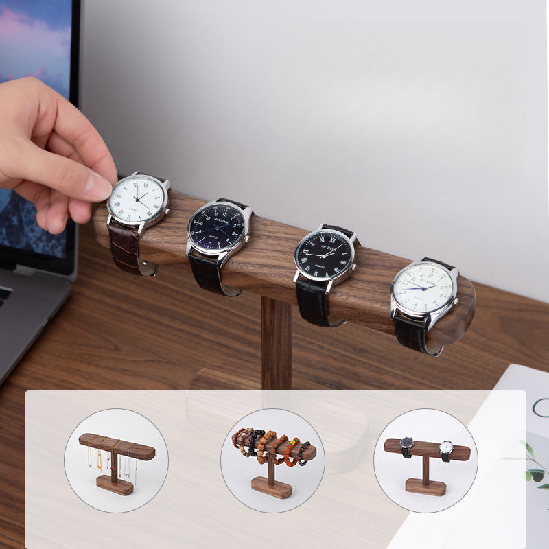 Handcrafted black walnut watch stand styled on a wooden desk beside everyday accessories.
