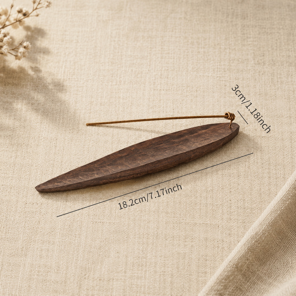 Side view of a handcrafted black walnut incense holder with a lit incense stick on a wooden table.