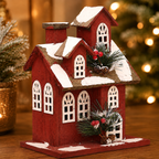 Close-up of the handcrafted wooden Christmas house featuring snow-covered rooftops, festive greenery, and warm LED lighting.