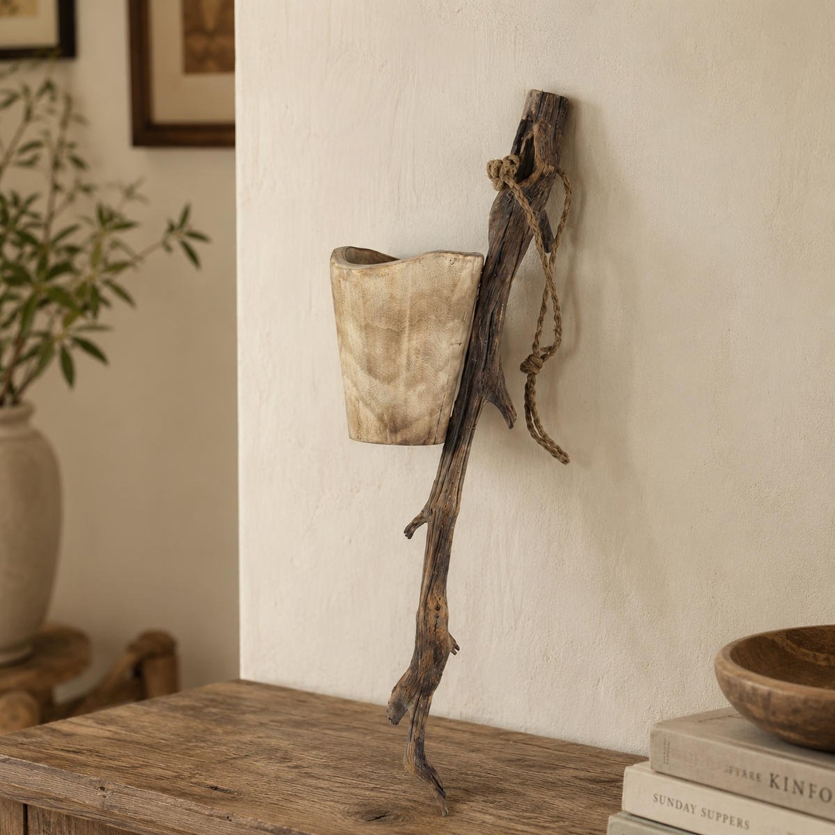 Natural paulownia wood hanging planter holding small green plants, creating a warm botanical accent for indoor spaces.