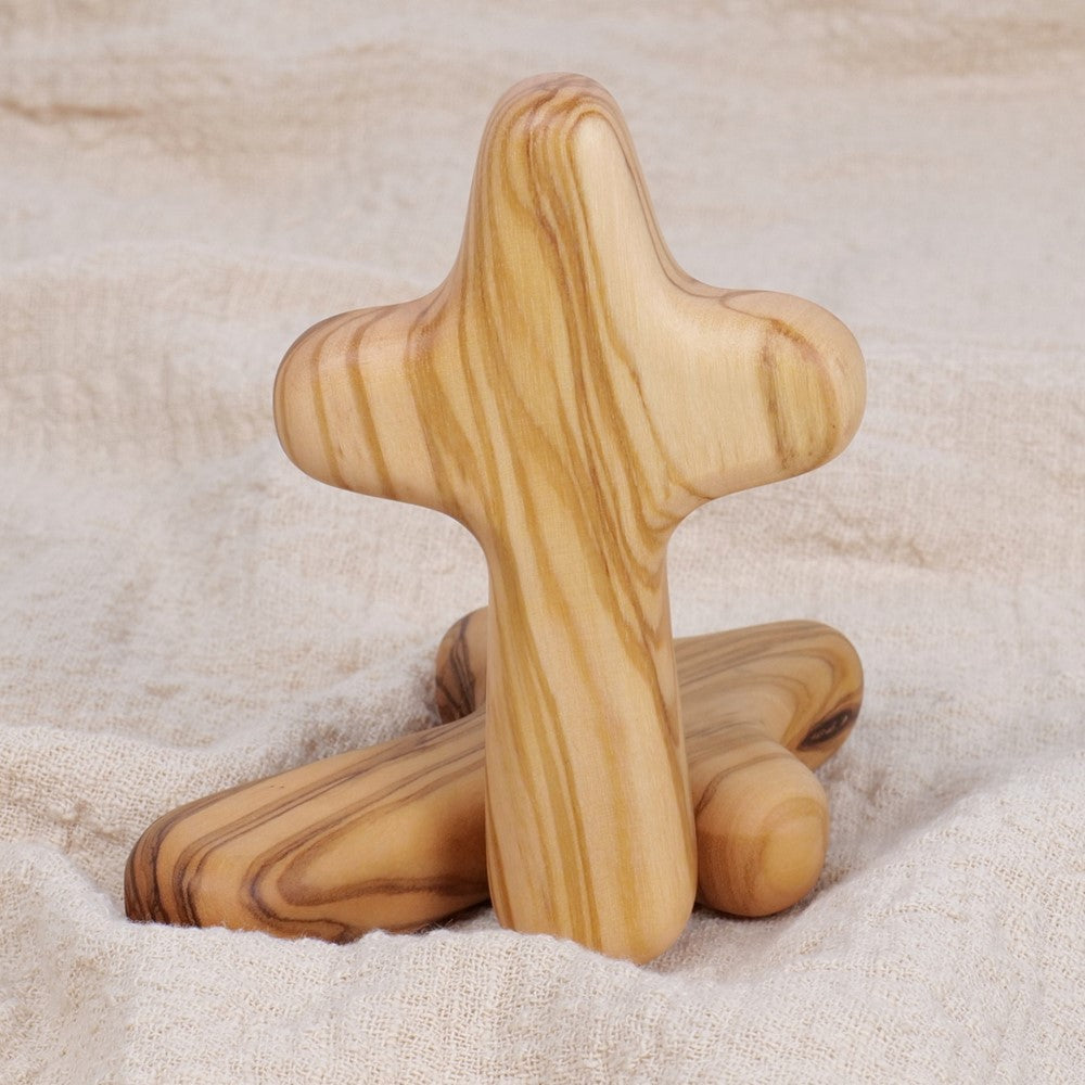 Close-up of a handcrafted olive wood comfort cross showing the unique grain and hand-sanded finish.