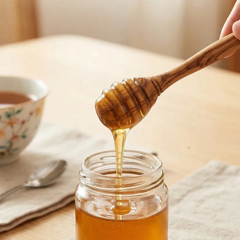 Close-up of handcrafted olive wood honey dipper stick highlighting smooth finish and natural wood grain.