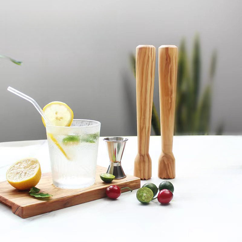 Hand using an olive wood lemon squeezer to crush citrus and ice for fresh cocktails and mixed drinks.