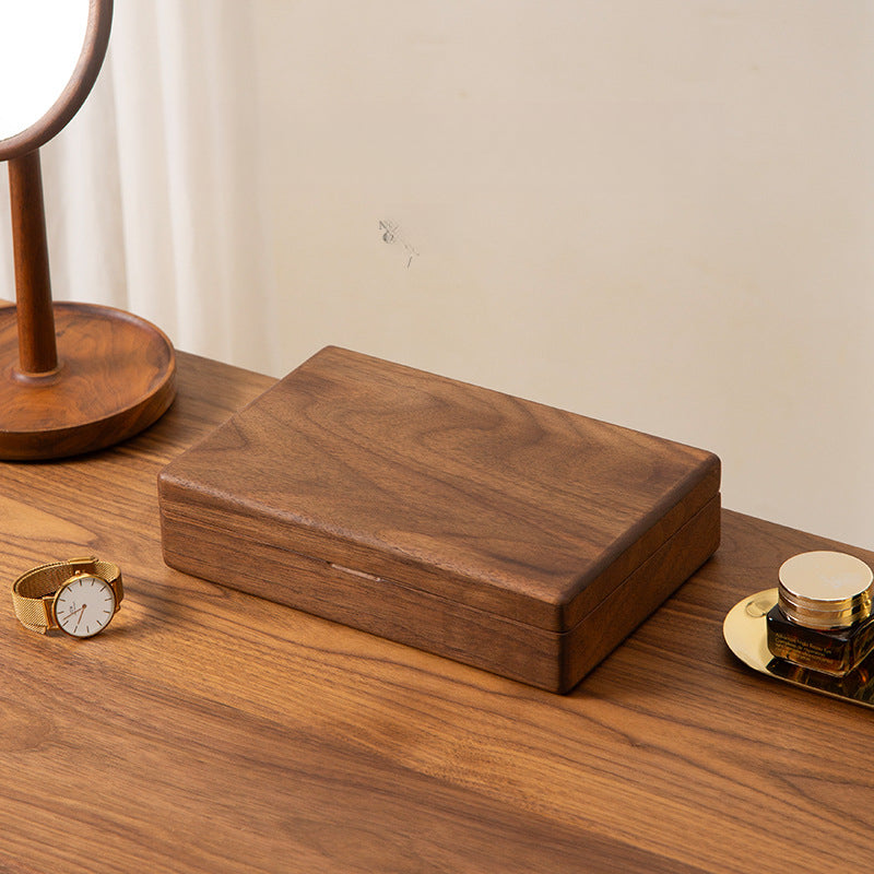 Personalized black walnut jewelry box displayed on a wooden dresser with everyday jewelry in a warm home setting.