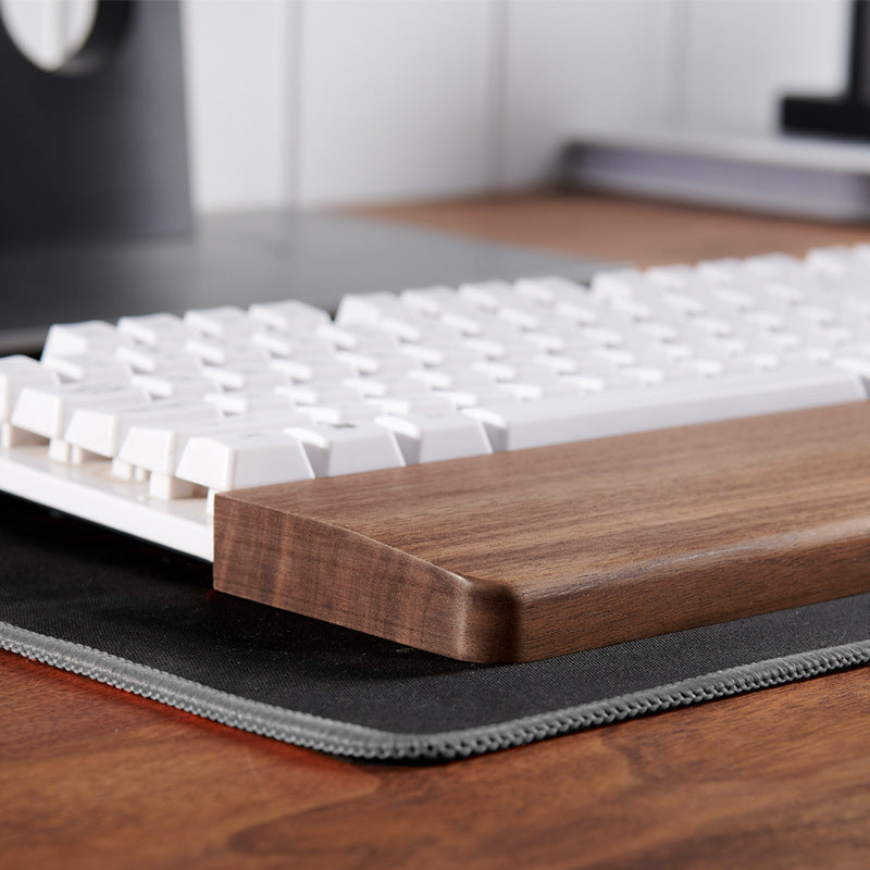 Solid black walnut keyboard wrist rest on a modern desk setup for everyday work and gaming.