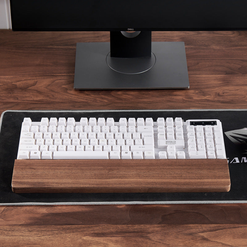 Handcrafted personalized black walnut keyboard wrist rest placed in front of a mechanical keyboard for comfortable typing.