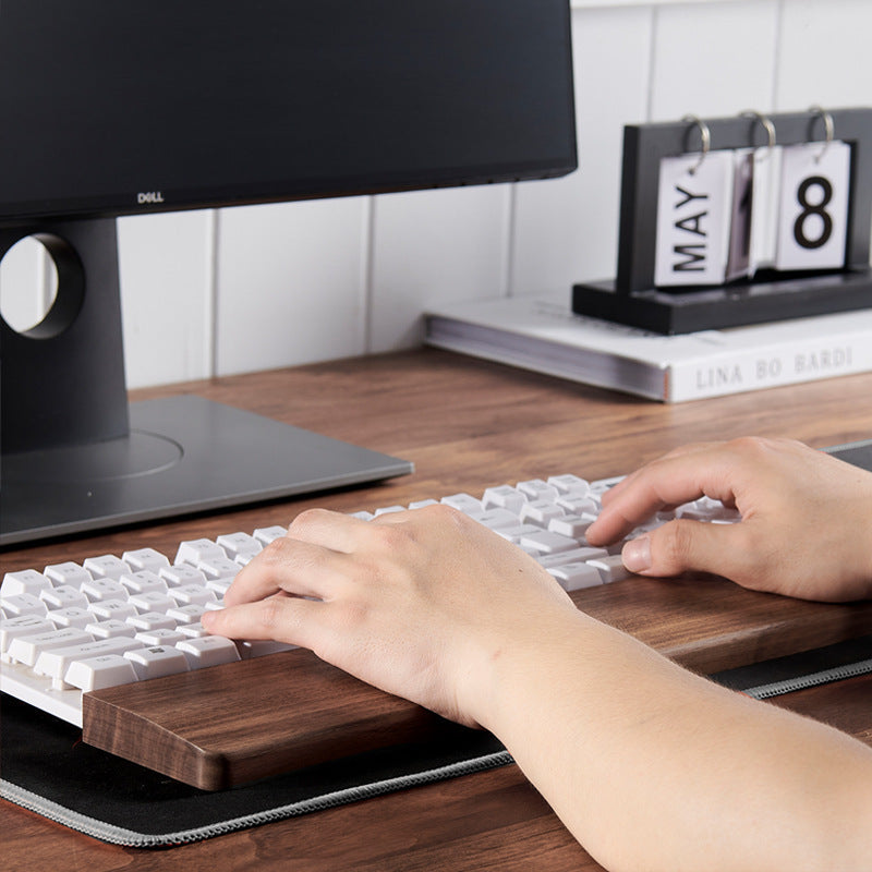 Ergonomic black walnut keyboard wrist rest supporting wrists during long typing sessions.