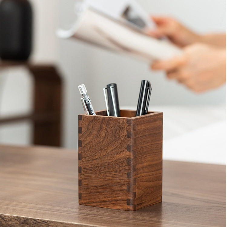 Handcrafted personalized black walnut pen holder with pens on a modern wooden desk.