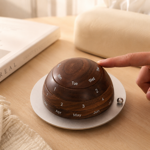 Black walnut perpetual calendar displayed on a desk beside books and home décor, adding warmth and timeless style to a workspace.