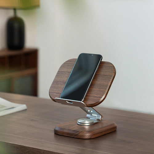 Solid black walnut phone and tablet stand supporting a smartphone on a modern desk.