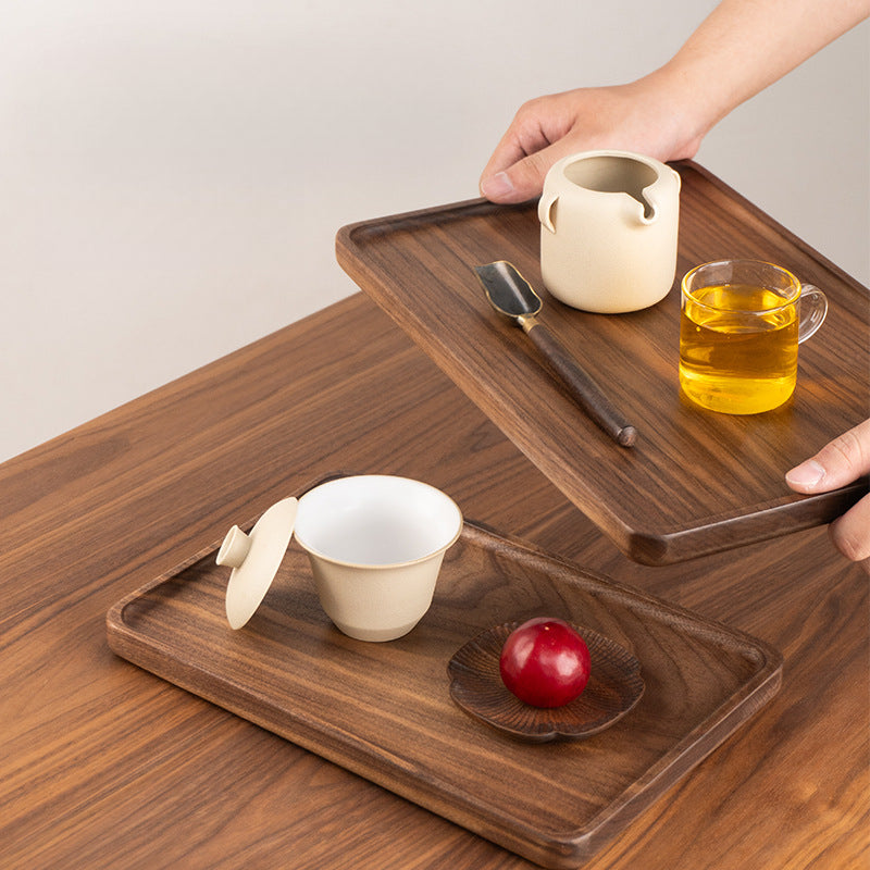 Solid black walnut serving tray used for serving tea and drinks on a wooden table in a cozy home.