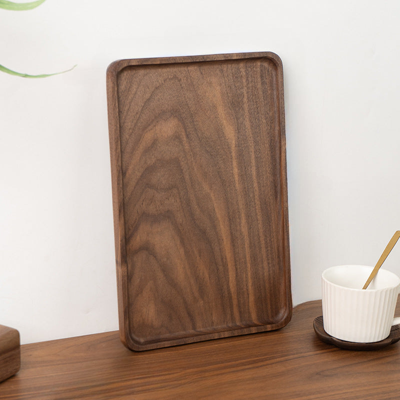 Handcrafted black walnut serving tray holding tea cups and a ceramic pitcher for a relaxing tea break.