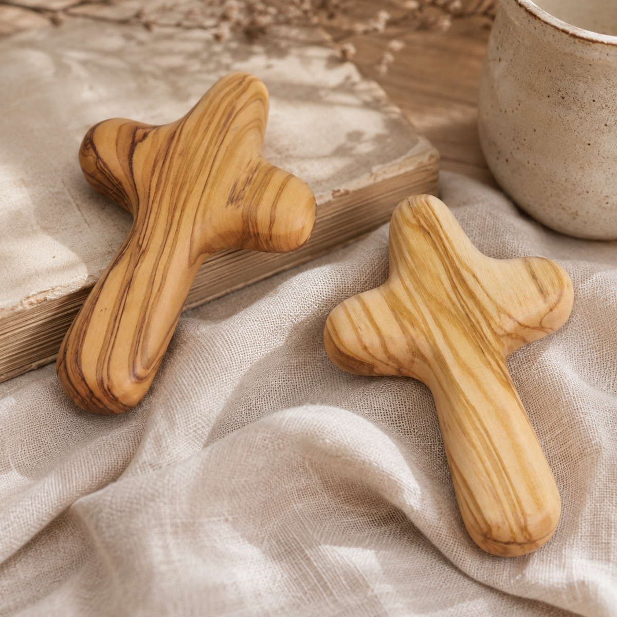 Handcrafted olive wood comfort cross resting beside a book and warm ceramic mug, creating a peaceful space for prayer, reflection, and daily comfort.