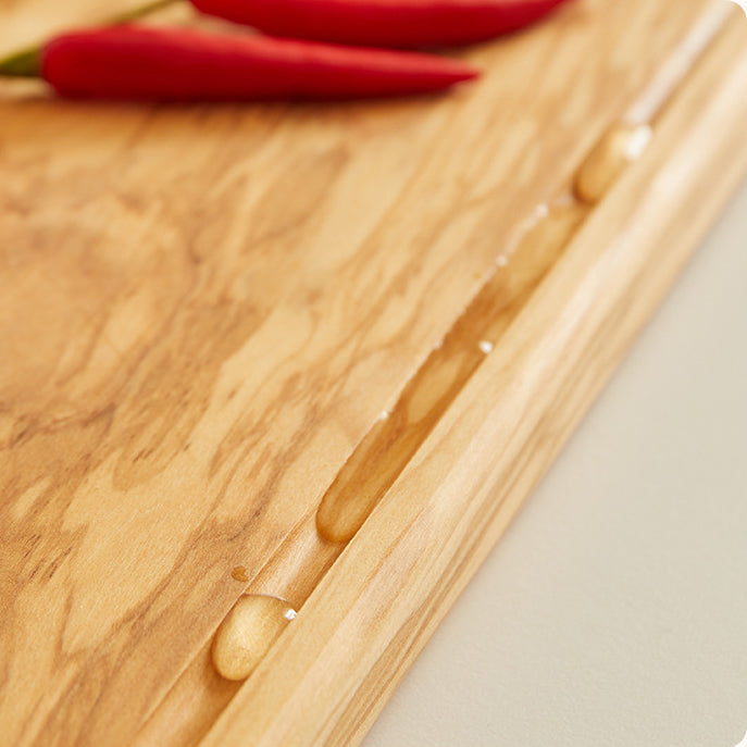 Close-up of a handcrafted olive wood steak serving board highlighting the natural grain, smooth finish, and carved juice groove.