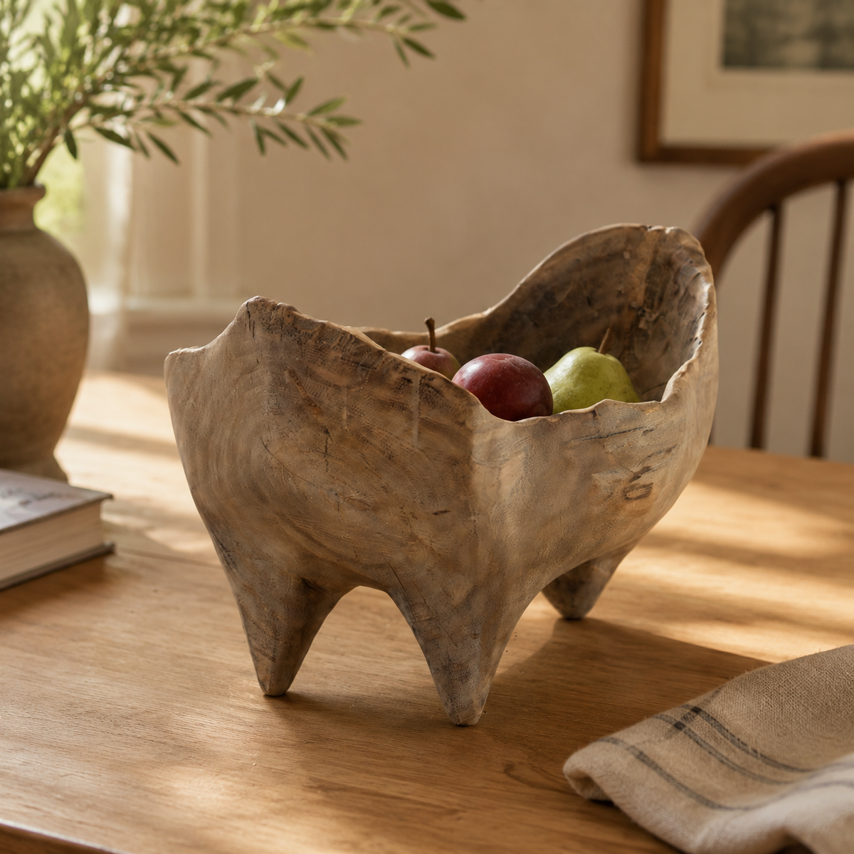 Handcrafted rustic wooden fruit bowl displayed on a dining table with fresh fruit, highlighting its organic shape and natural character.