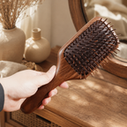 Side view of a black walnut wooden paddle brush with a curved solid wood body.