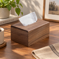 Black walnut tissue box cover with a clean rectangular shape, displayed on a wooden tabletop in warm natural light.