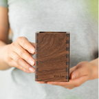 Personalized black walnut pen holder with engraved text, displayed on a desk in a warm home office setting.