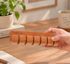Personalized cherry wood cable organizer with multiple slots for keeping charging cords and USB cables neat on a desk or wall.