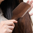 Natural wood hair brush displayed on a warm bathroom vanity with linen and wood textures.
