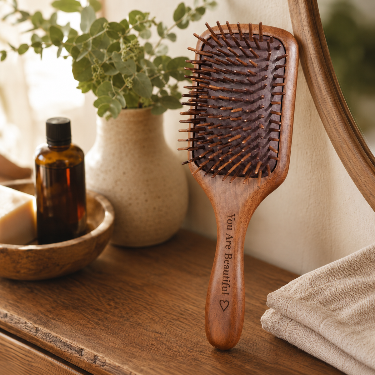 Personalized black walnut wooden paddle hair brush with wooden pins and an engraved handle, styled in warm natural light.