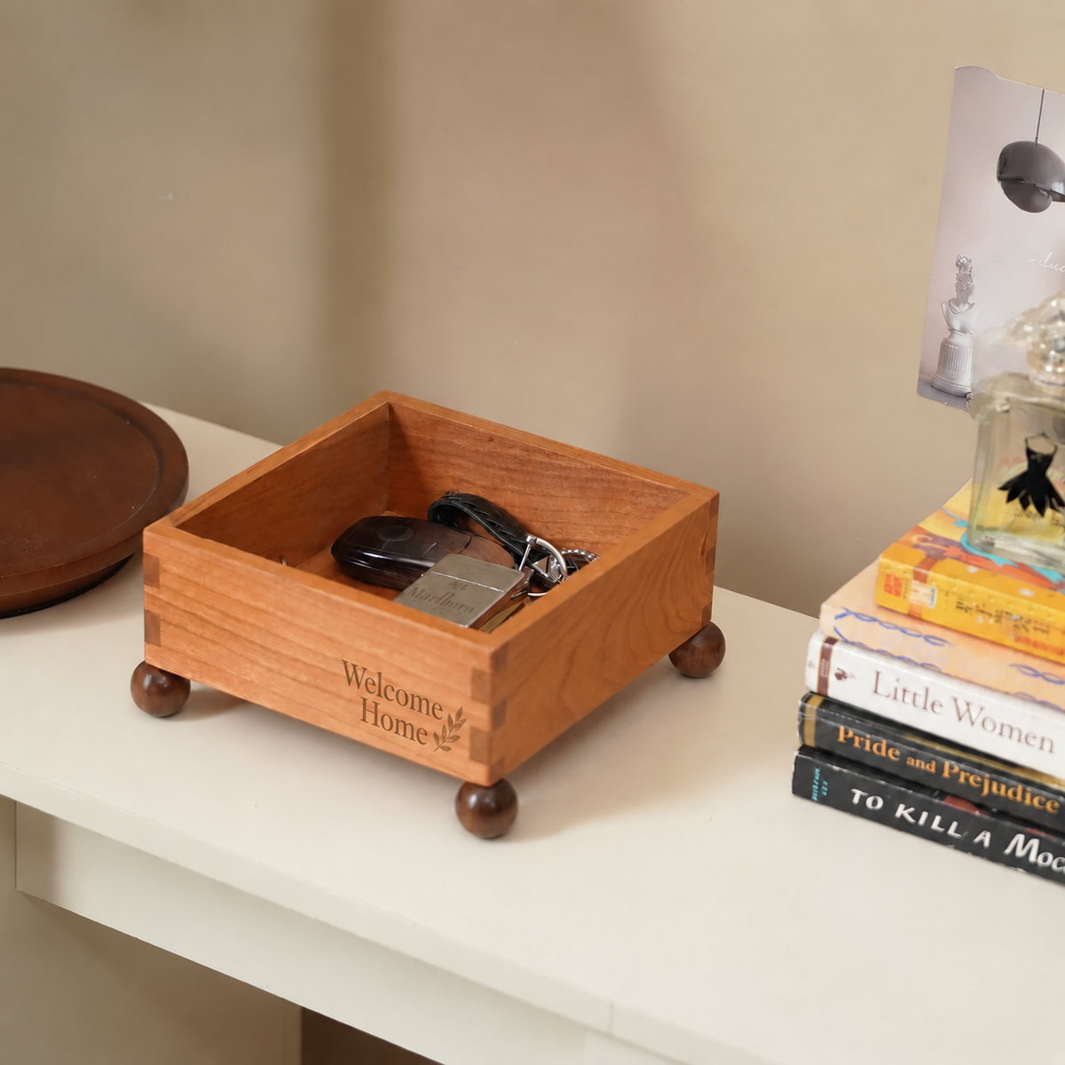 Personalized cherry wood catchall storage box with raised sides and small feet, holding keys and everyday essentials on a home entryway table.
